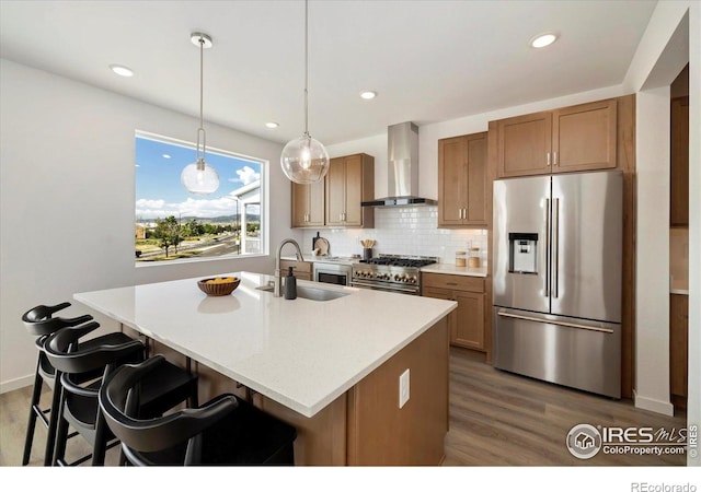 900 Eldorado Ln, Louisville, CO 80027 - kitchen with appliances with stainless steel finishes, wall chimney exhaust hood, wood finished floors, decorative backsplash, and a kitchen island with sink