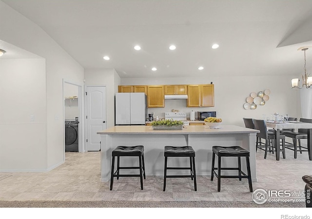1774 Thrive Dr, Windsor, CO 80550 - kitchen featuring white appliances, washer / dryer, under cabinet range hood, recessed lighting, and a breakfast bar