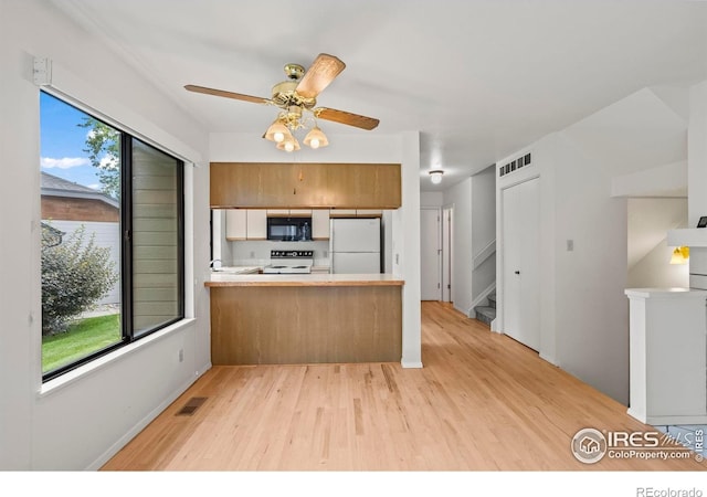 4636 Chestnut Ln, Boulder, CO 80301 - kitchen with black microwave, freestanding refrigerator, stove, light wood finished floors, and a peninsula