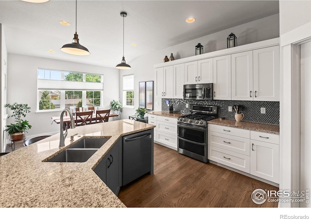 401 Cascade Ct, Johnstown, CO 80534 - kitchen with appliances with stainless steel finishes, dark wood-style flooring, white cabinetry, backsplash, and decorative light fixtures