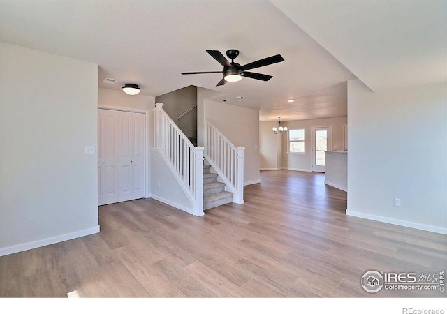 4319 Primrose Ln, Evans, CO 80620 - unfurnished living room featuring stairs, a chandelier, a ceiling fan, and light wood-style floors