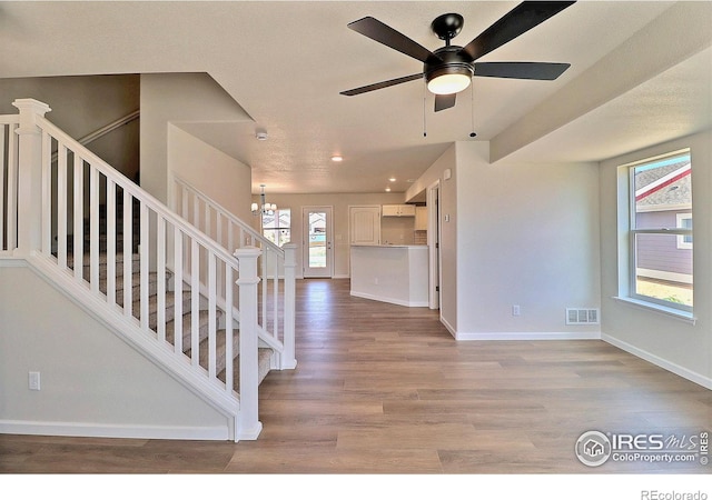 4319 Primrose Ln, Evans, CO 80620 - unfurnished living room featuring wood finished floors, stairway, a ceiling fan, recessed lighting, and a chandelier