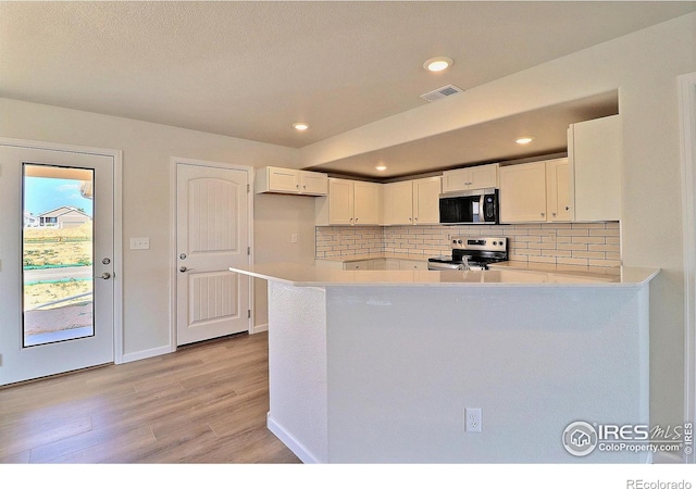 4319 Primrose Ln, Evans, CO 80620 - kitchen featuring stainless steel appliances, white cabinetry, light wood-style floors, tasteful backsplash, and light countertops