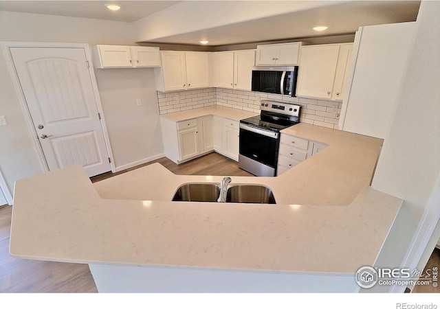 4319 Primrose Ln, Evans, CO 80620 - kitchen featuring appliances with stainless steel finishes, backsplash, white cabinets, light wood-style floors, and recessed lighting