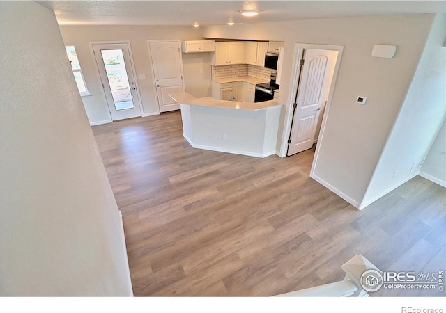 4319 Primrose Ln, Evans, CO 80620 - kitchen with appliances with stainless steel finishes, wood finished floors, backsplash, light countertops, and a peninsula