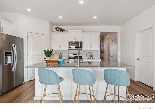 2239 Base St, Fort Lupton, CO 80621 - kitchen with stainless steel appliances, wood finished floors, tasteful backsplash, a breakfast bar area, and recessed lighting