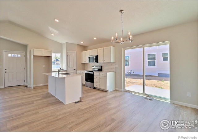 4315 Primrose Ln, Evans, CO 80620 - kitchen with stainless steel appliances, a chandelier, light wood-style floors, white cabinetry, and vaulted ceiling