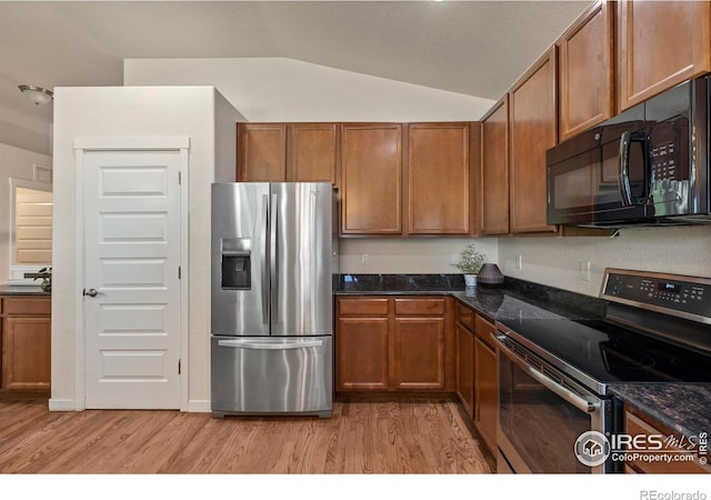 2968 Hydra Dr, Loveland, CO 80537 - kitchen with appliances with stainless steel finishes, light wood finished floors, brown cabinets, lofted ceiling, and dark stone countertops