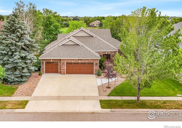 4283 Golf Vista Dr, Loveland, CO 80537 - craftsman-style home featuring a shingled roof, brick siding, driveway, an attached garage, and a front lawn