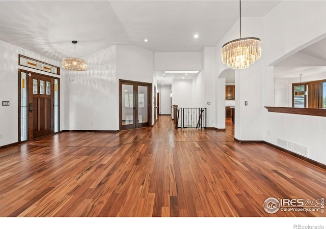 4283 Golf Vista Dr, Loveland, CO 80537 - unfurnished living room featuring a chandelier, high vaulted ceiling, hardwood / wood-style flooring, arched walkways, and french doors