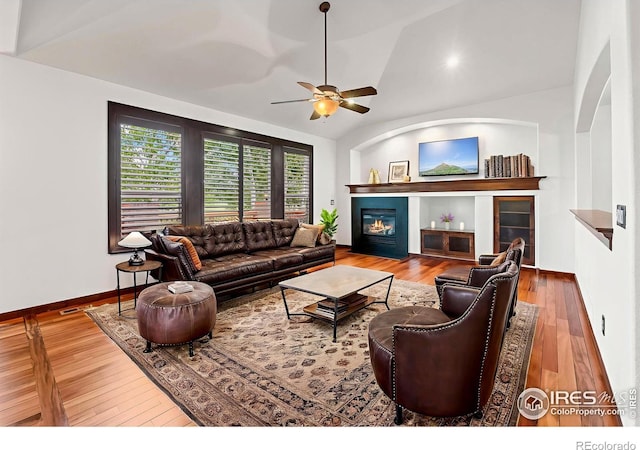 4283 Golf Vista Dr, Loveland, CO 80537 - living room featuring vaulted ceiling, a ceiling fan, wood finished floors, and a glass covered fireplace