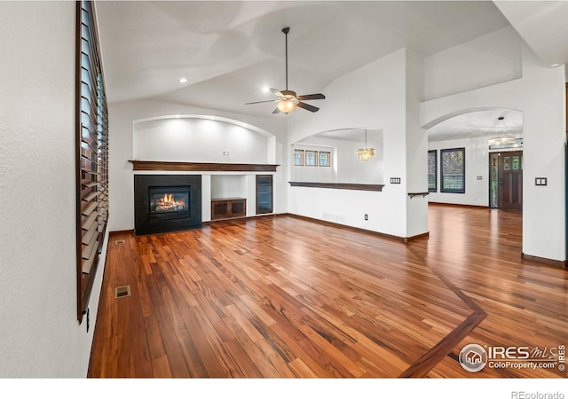 4283 Golf Vista Dr, Loveland, CO 80537 - unfurnished living room featuring a ceiling fan, hardwood / wood-style flooring, a glass covered fireplace, arched walkways, and lofted ceiling