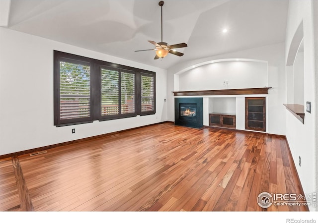 4283 Golf Vista Dr, Loveland, CO 80537 - unfurnished living room featuring a glass covered fireplace, a ceiling fan, vaulted ceiling, and hardwood / wood-style flooring