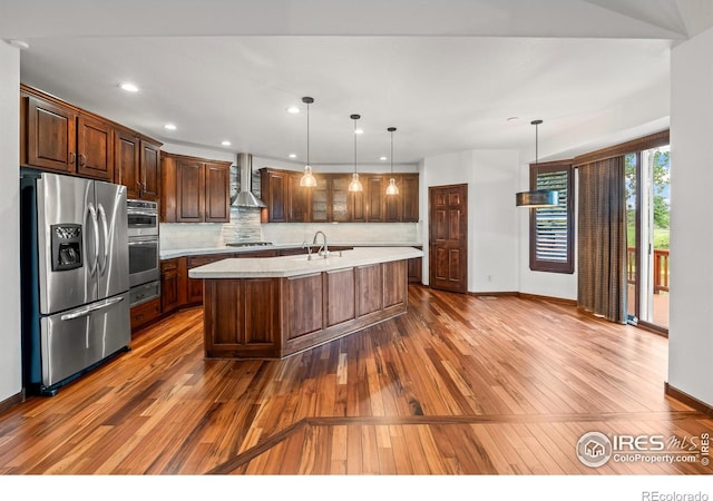 4283 Golf Vista Dr, Loveland, CO 80537 - kitchen featuring appliances with stainless steel finishes, wall chimney range hood, light countertops, hardwood / wood-style flooring, and decorative backsplash