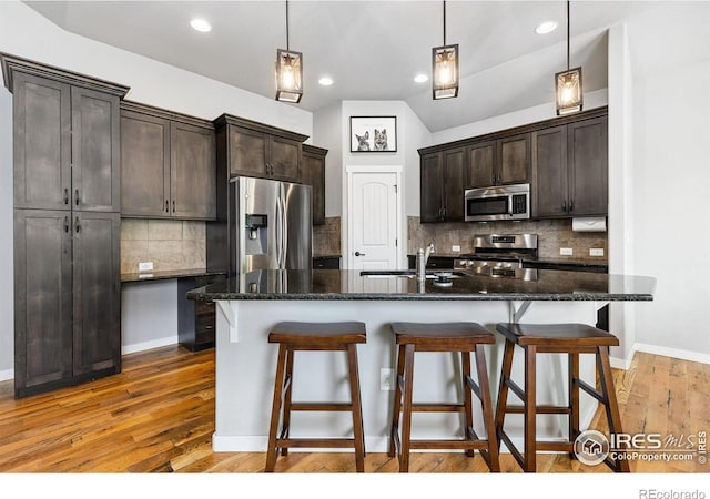 1625 Glacier Ave, Berthoud, CO 80513 - kitchen featuring stainless steel appliances, dark brown cabinetry, a breakfast bar, backsplash, and recessed lighting