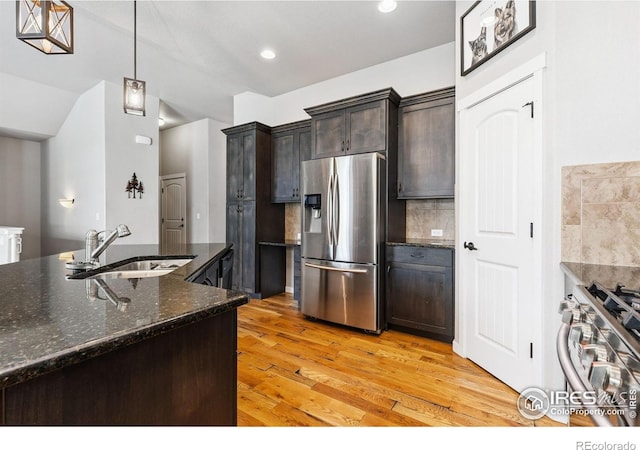 1625 Glacier Ave, Berthoud, CO 80513 - kitchen featuring appliances with stainless steel finishes, light wood-type flooring, tasteful backsplash, dark brown cabinetry, and dark stone countertops