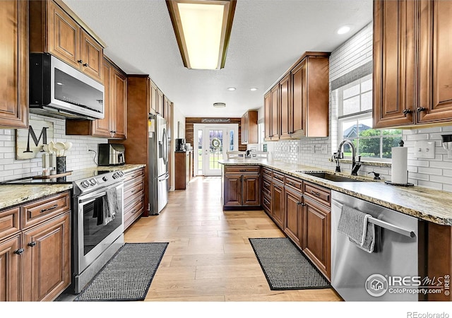 1115 Kestrel Rd, Eaton, CO 80615 - kitchen featuring appliances with stainless steel finishes, decorative backsplash, light wood-style flooring, light stone counters, and recessed lighting