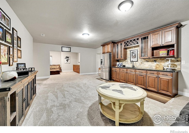 1115 Kestrel Rd, Eaton, CO 80615 - kitchen featuring stainless steel fridge with ice dispenser, dark countertops, tasteful backsplash, light colored carpet, and glass insert cabinets