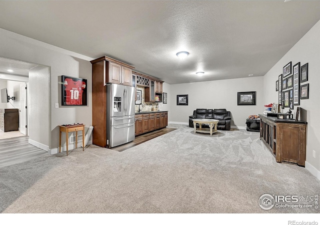 1115 Kestrel Rd, Eaton, CO 80615 - kitchen featuring stainless steel fridge with ice dispenser, open floor plan, carpet, and a textured ceiling