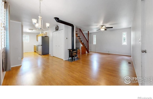5001 W County Road 38 E, Fort Collins, CO 80526 - unfurnished living room with a wood stove, a ceiling fan, light wood finished floors, and a chandelier