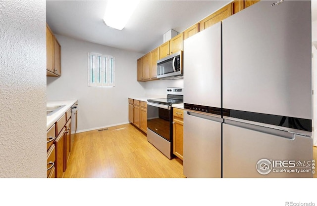 5001 W County Road 38 E, Fort Collins, CO 80526 - kitchen featuring appliances with stainless steel finishes, light wood finished floors, and light countertops