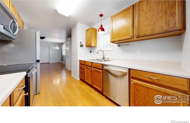 5001 W County Road 38 E, Fort Collins, CO 80526 - kitchen featuring appliances with stainless steel finishes, light wood-style floors, pendant lighting, light countertops, and brown cabinets