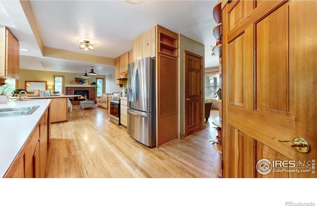 2319 Cotswold Ct, Fort Collins, CO 80526 - kitchen featuring stainless steel appliances, open floor plan, a fireplace, and light wood-type flooring