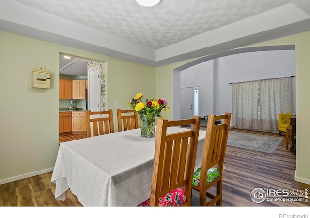 1169 Cooke Ct, Erie, CO 80516 - dining area with wood finished floors, arched walkways, and a textured ceiling