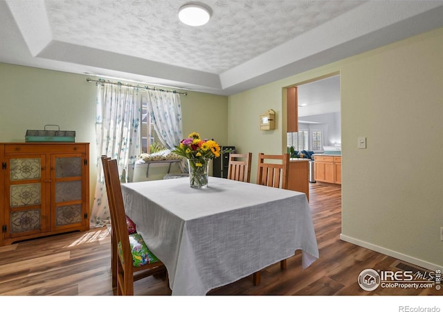 1169 Cooke Ct, Erie, CO 80516 - dining area featuring a textured ceiling, a tray ceiling, and wood finished floors