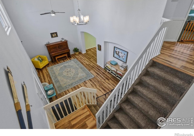 1169 Cooke Ct, Erie, CO 80516 - staircase with wood finished floors, a chandelier, a high ceiling, arched walkways, and a ceiling fan