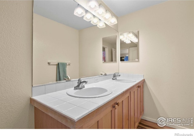 1169 Cooke Ct, Erie, CO 80516 - bathroom with double vanity, wood finished floors, and a textured wall