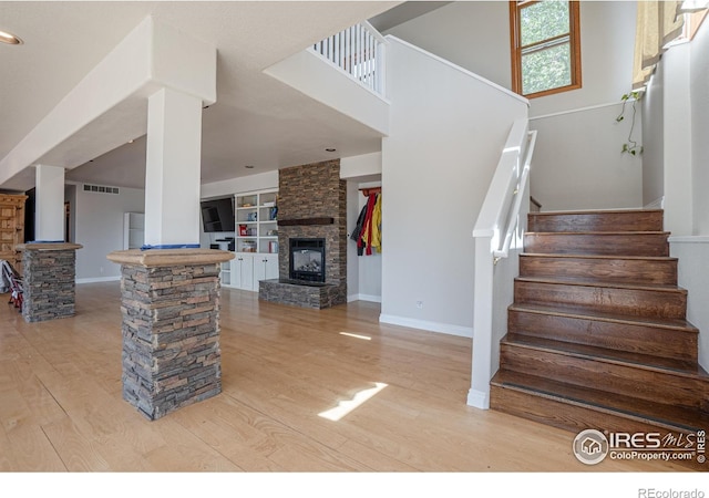 952 Steamboat Valley Rd, Lyons, CO 80540 - staircase with decorative columns, wood finished floors, built in shelves, and a stone fireplace