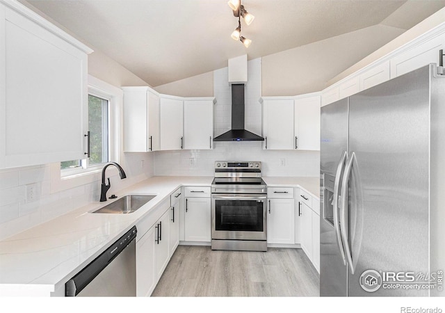 4386 Suncreek Dr, Loveland, CO 80538 - kitchen with stainless steel appliances, vaulted ceiling, wall chimney exhaust hood, light wood-type flooring, and white cabinetry