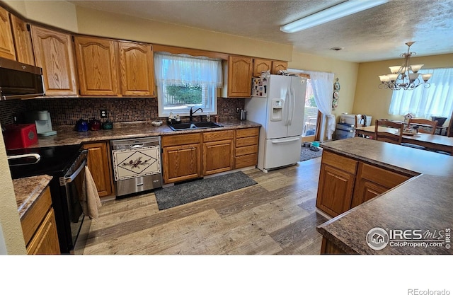 420 Applewood St, Brush, CO 80723 - kitchen with appliances with stainless steel finishes, a chandelier, light wood-type flooring, brown cabinets, and a textured ceiling