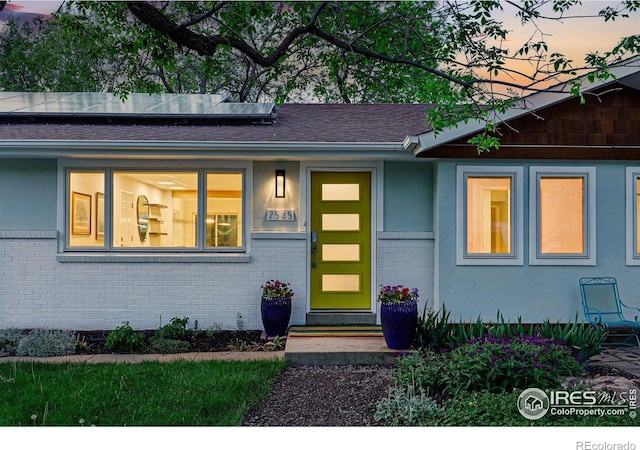 2545 Woodstock Pl, Boulder, CO 80305 - exterior entry at dusk with roof mounted solar panels, brick siding, and roof with shingles