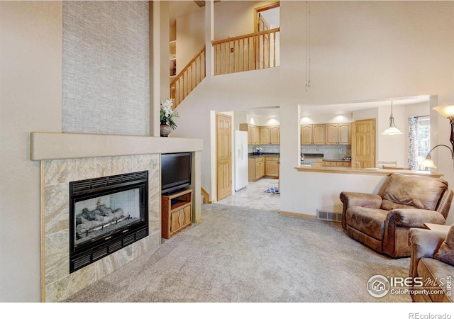 4500 Seneca St Unit 11, Fort Collins, CO 80526 - living area featuring light carpet, a tiled fireplace, a high ceiling, and stairway
