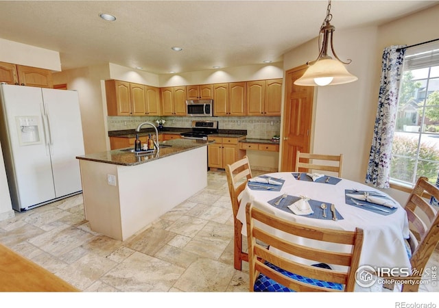 4500 Seneca St Unit 11, Fort Collins, CO 80526 - kitchen with appliances with stainless steel finishes, backsplash, an island with sink, dark stone countertops, and decorative light fixtures