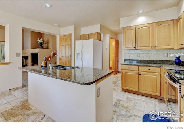 4500 Seneca St Unit 11, Fort Collins, CO 80526 - kitchen with stone tile flooring, white fridge with ice dispenser, dark stone counters, a center island with sink, and recessed lighting