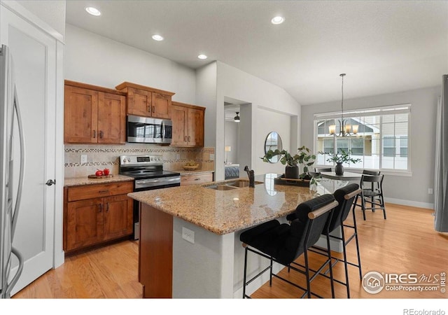 1062 Mt Columbia Dr, Severance, CO 80550 - kitchen featuring appliances with stainless steel finishes, brown cabinets, tasteful backsplash, light stone countertops, and light wood-style flooring