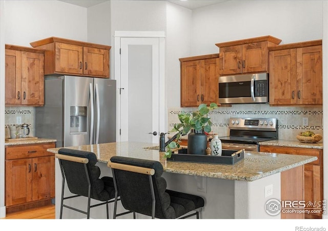 1062 Mt Columbia Dr, Severance, CO 80550 - kitchen featuring stainless steel appliances, tasteful backsplash, brown cabinets, and a breakfast bar area