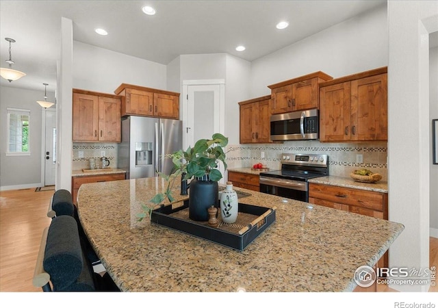 1062 Mt Columbia Dr, Severance, CO 80550 - kitchen with stainless steel appliances, brown cabinets, tasteful backsplash, light wood-type flooring, and a center island with sink