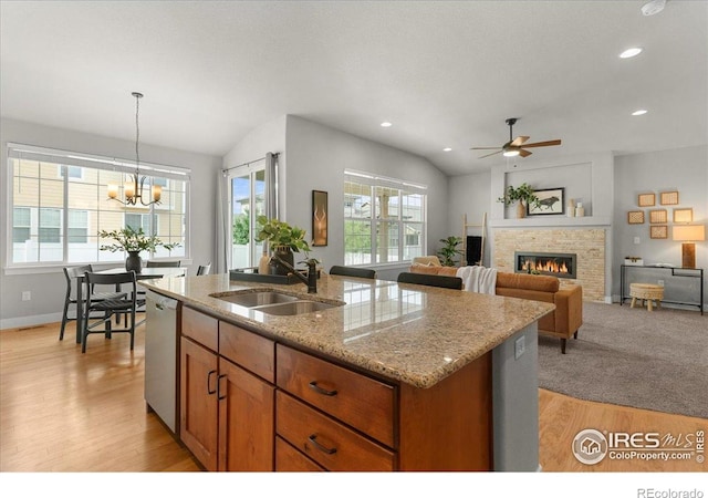 1062 Mt Columbia Dr, Severance, CO 80550 - kitchen with brown cabinetry, a glass covered fireplace, light wood-type flooring, a kitchen island with sink, and ceiling fan