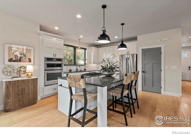 4306 Dixon St, Timnath, CO 80547 - kitchen with recessed lighting, decorative backsplash, a breakfast bar area, white cabinetry, and light wood-style flooring