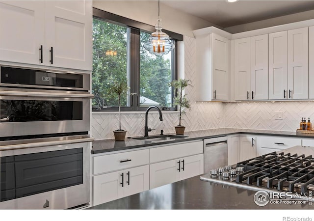 4306 Dixon St, Timnath, CO 80547 - kitchen with appliances with stainless steel finishes, dark countertops, decorative backsplash, white cabinetry, and hanging light fixtures