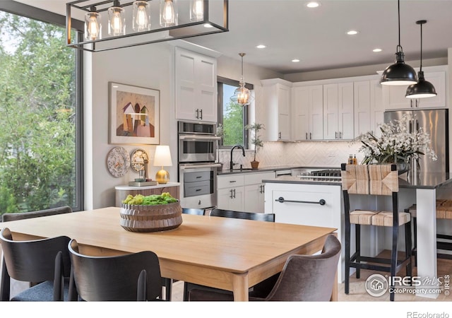4306 Dixon St, Timnath, CO 80547 - kitchen with tasteful backsplash, white cabinets, appliances with stainless steel finishes, a kitchen island, and a kitchen bar