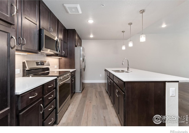 kitchen featuring hanging light fixtures, stainless steel appliances, sink, dark brown cabinetry, and light wood-type flooring