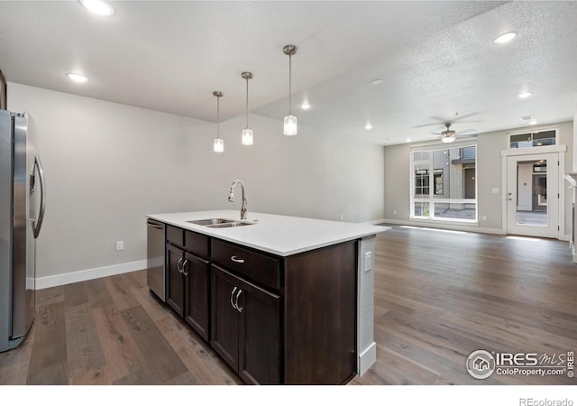 kitchen with a kitchen island with sink, hardwood / wood-style flooring, sink, pendant lighting, and appliances with stainless steel finishes