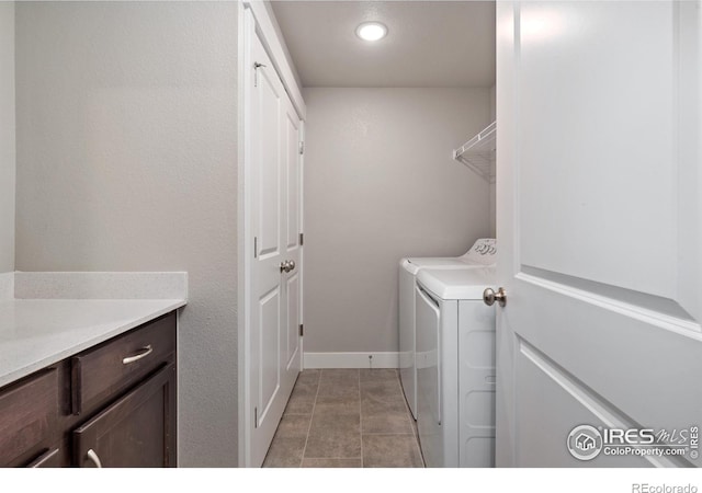 laundry area with independent washer and dryer, cabinets, and light tile patterned floors