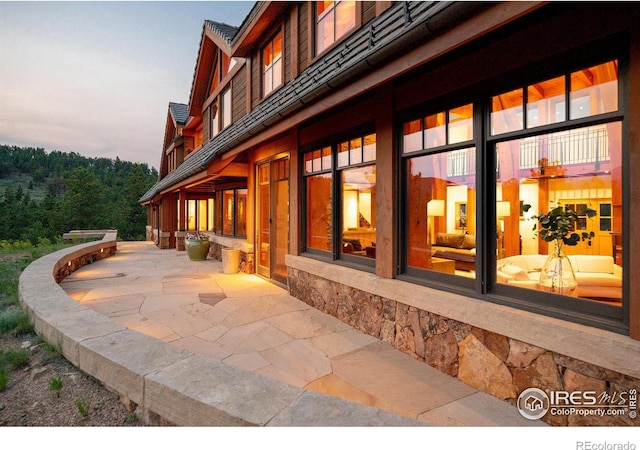 property exterior at dusk featuring a patio area