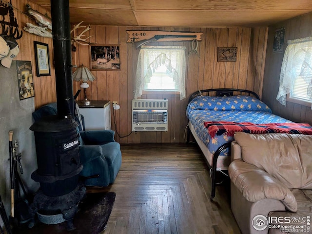 bedroom with dark parquet flooring, a wood stove, heating unit, wood walls, and wood ceiling